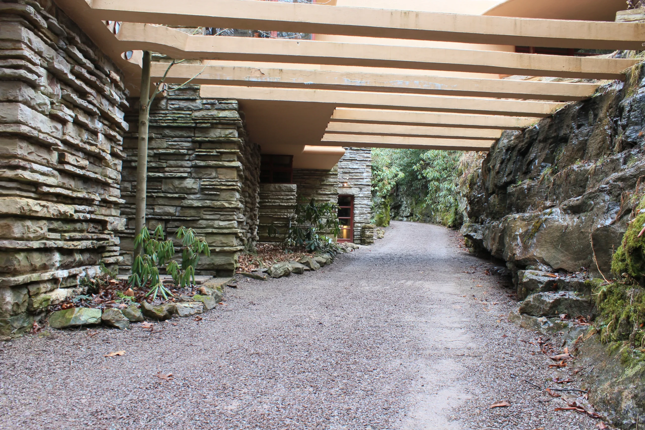Wejście do rezydencji Fallingwater, zaprojektowanej przez Franka Lloyda Wrighta, harmonijnie wkomponowane w otaczający krajobraz.